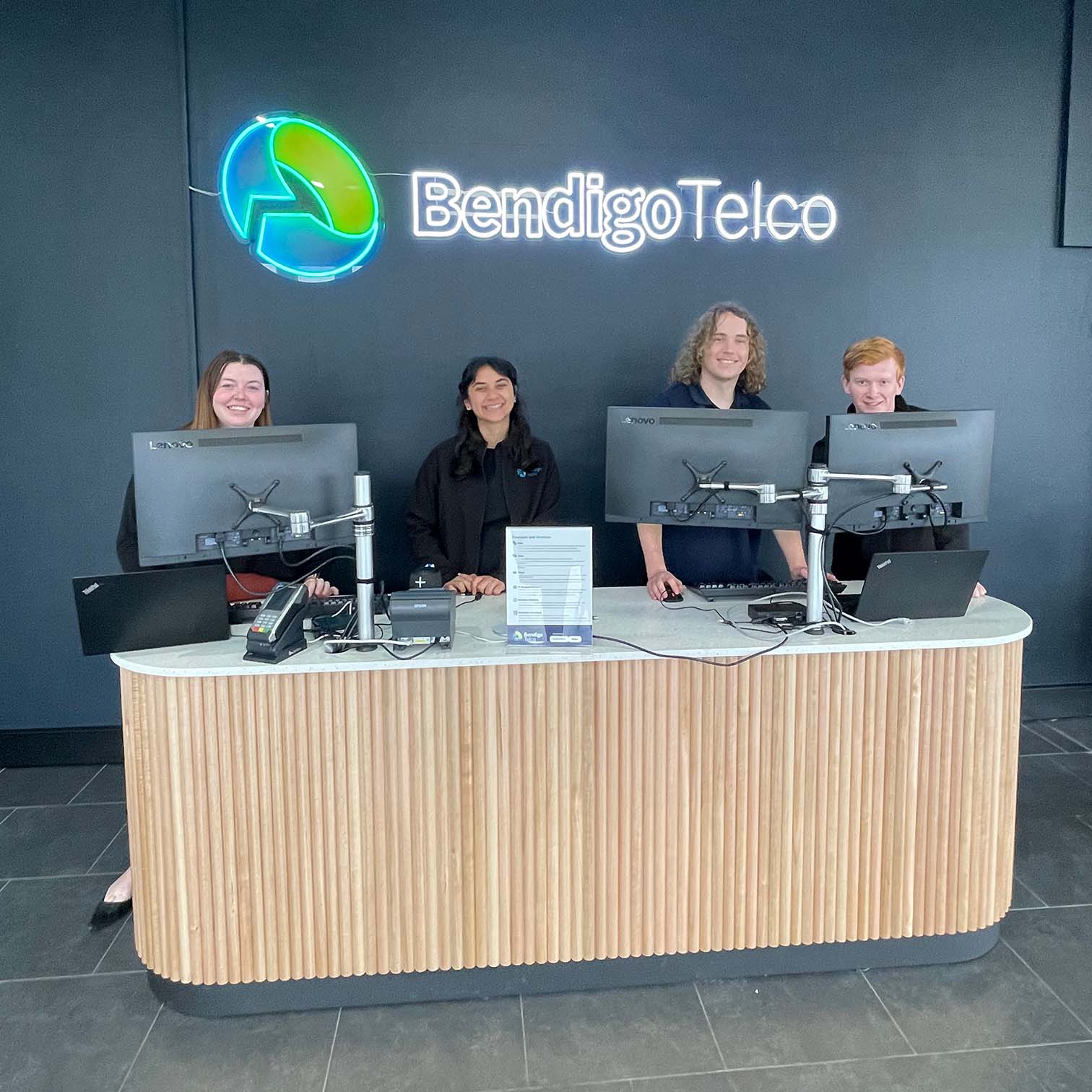 bendigo telco office with neon logo sign with counter and four employees